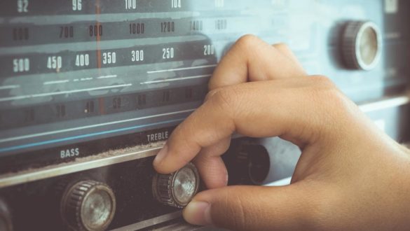 widok dłoni trzymającej palcami pokrętło w starym odtwarzaczu radiowym