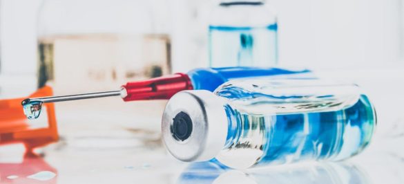 przewrócona wielorazowa fiolka z lekiem iniekcyjnym na blacie obok strzykawki