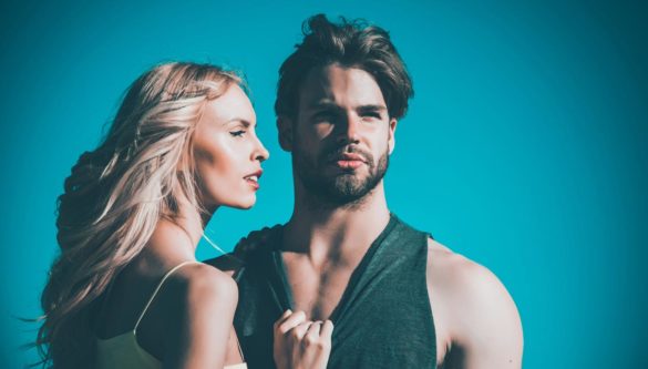 młoda, blondwłosa kobieta spoglądająca na młodego i umięśnionego, przystojnego mężczyznę z zarostem patrzącego w dal